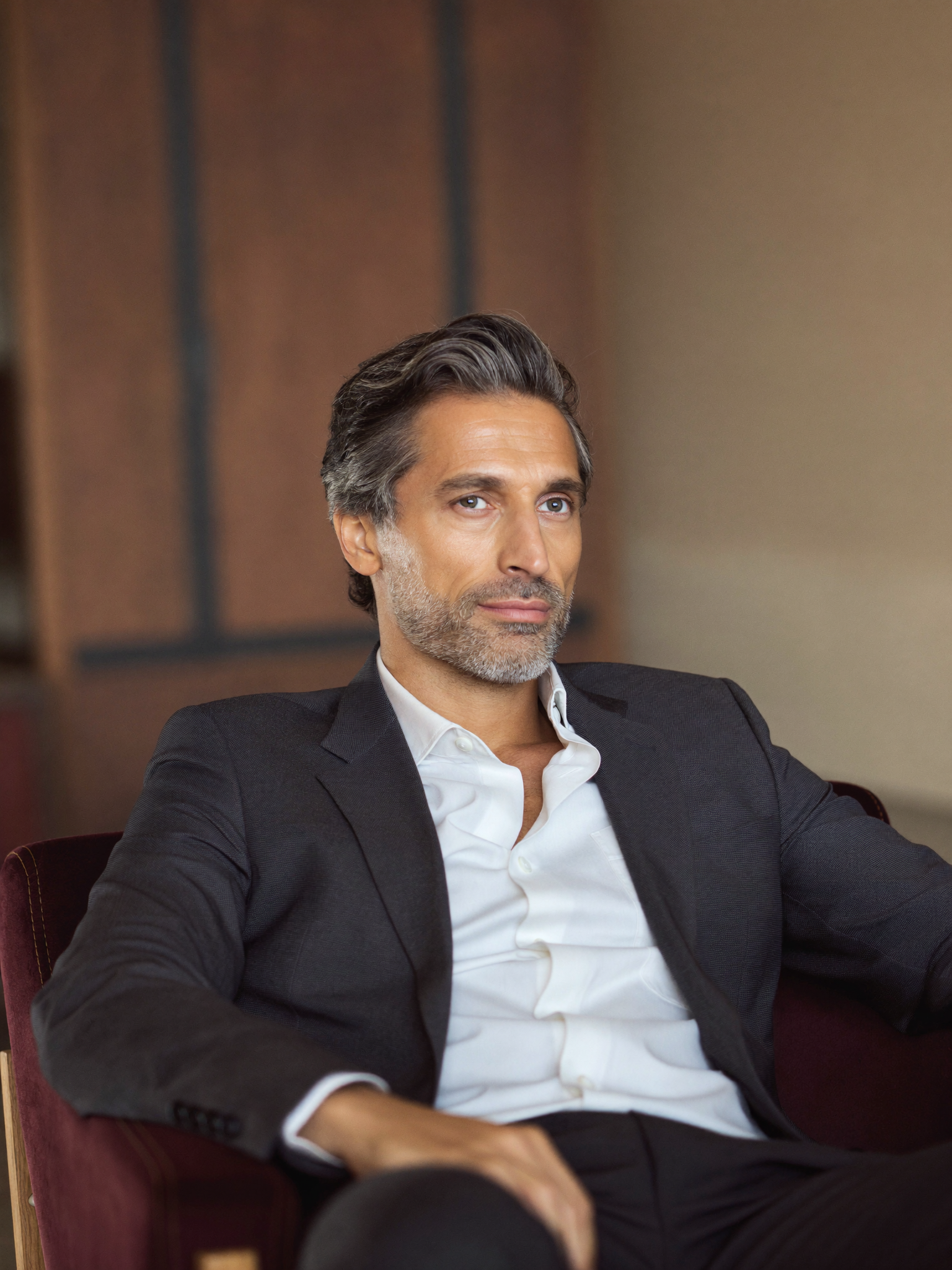 A distinguished, well-dressed professional man in warm natural light — looking rested, alert and quietly confident